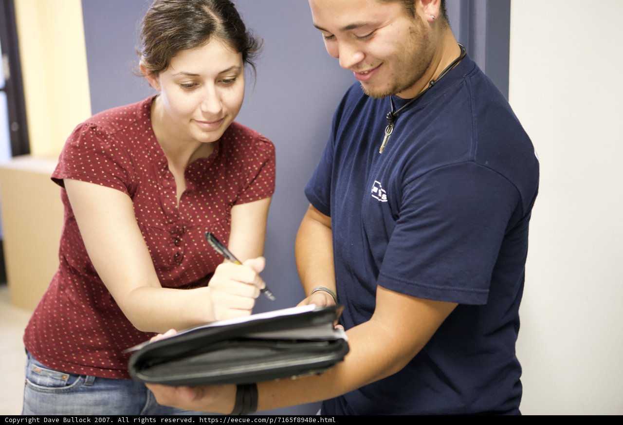 A couple reviewing paperwork Caption: A man and a woman examining a document featuring their jewelry and clothing accessories.
