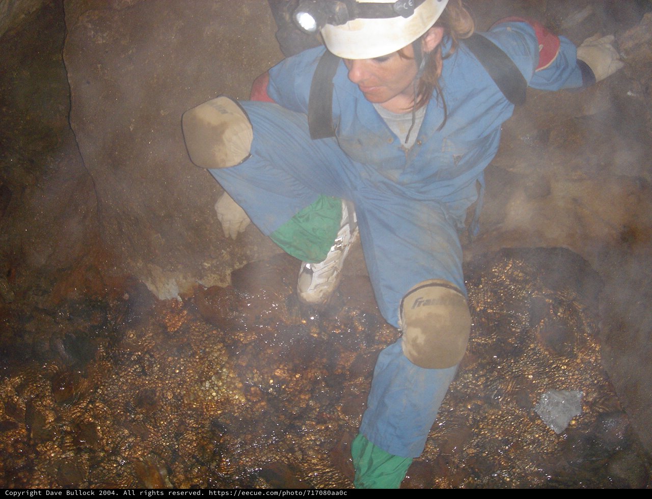 Spelunker Navigates Misty Underground Cave Passage