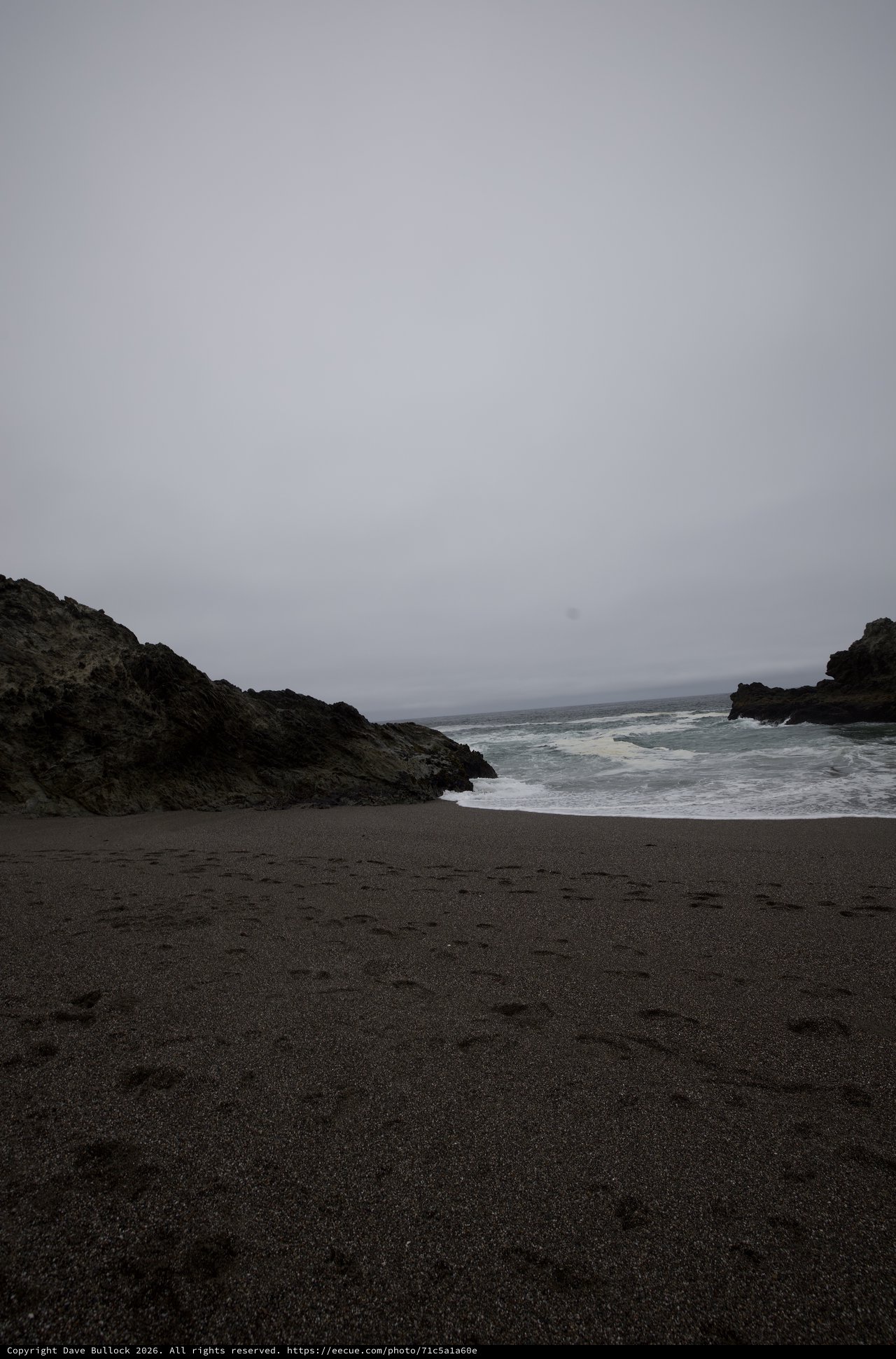 Dark Sand Cove Under Brooding Fog-Shrouded Skies