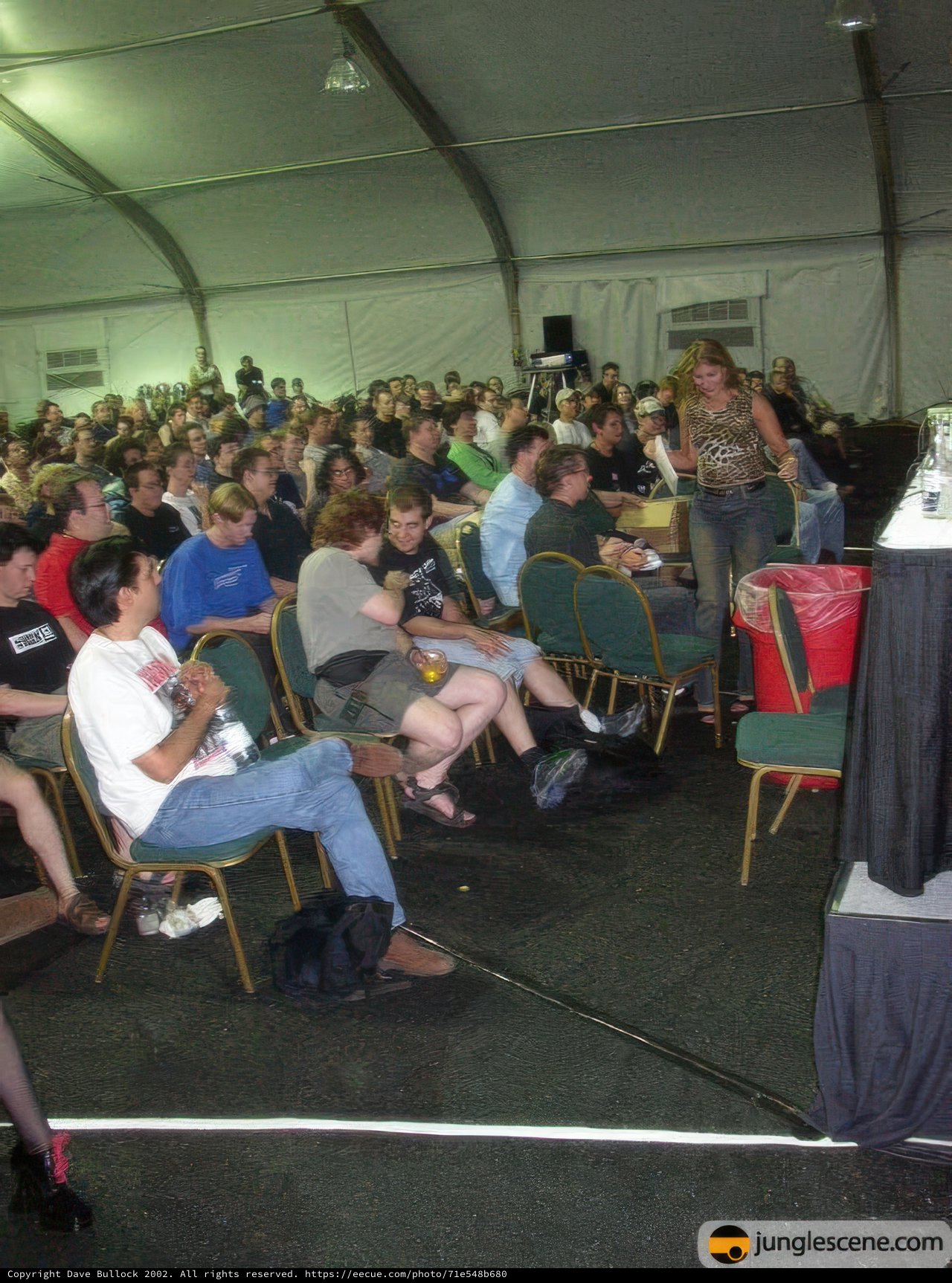 Tent Talk Caption: A crowd of 29 people sit in chairs, listening intently to the speaker at the Defcon 10 conference.