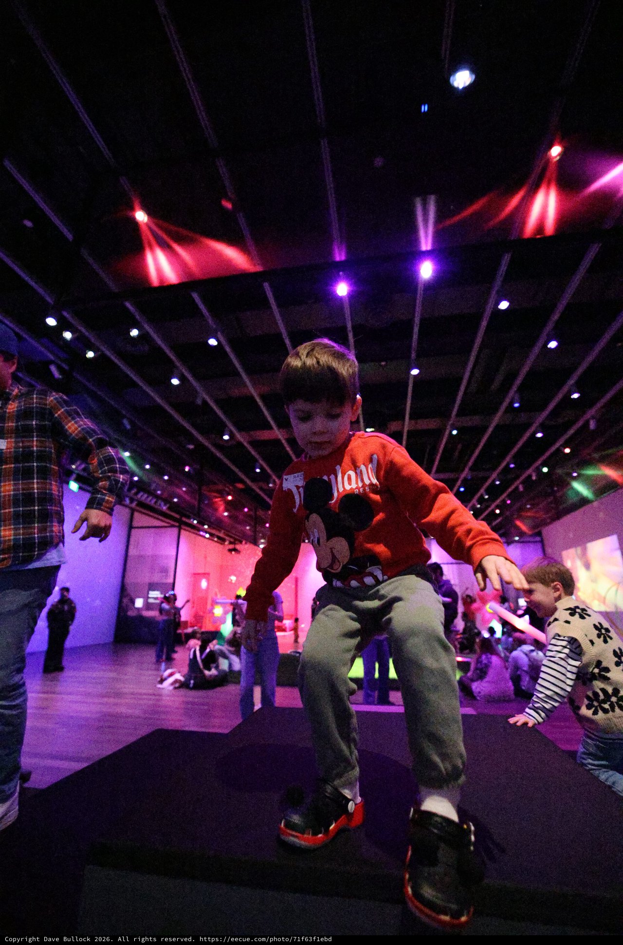 Child Dancing at Baby Rave Event Under Colorful Lights