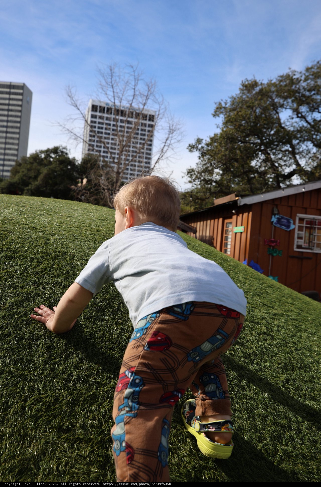 Toddler Climbing Hill in Urban Park Setting