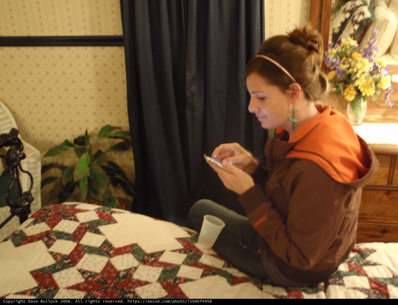 Young Woman Texting on Phone in Cozy Bedroom