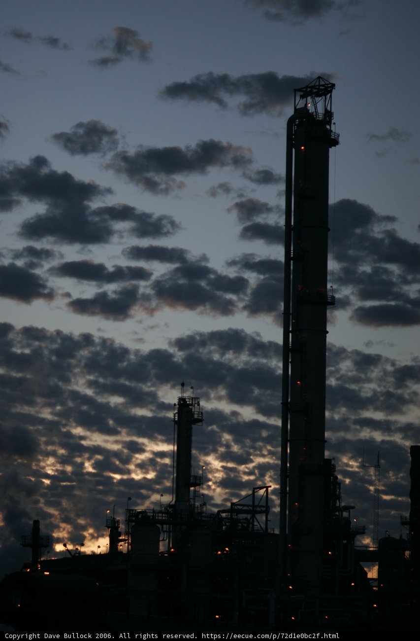 Glowing Refinery Towers Against a Dramatic Sky