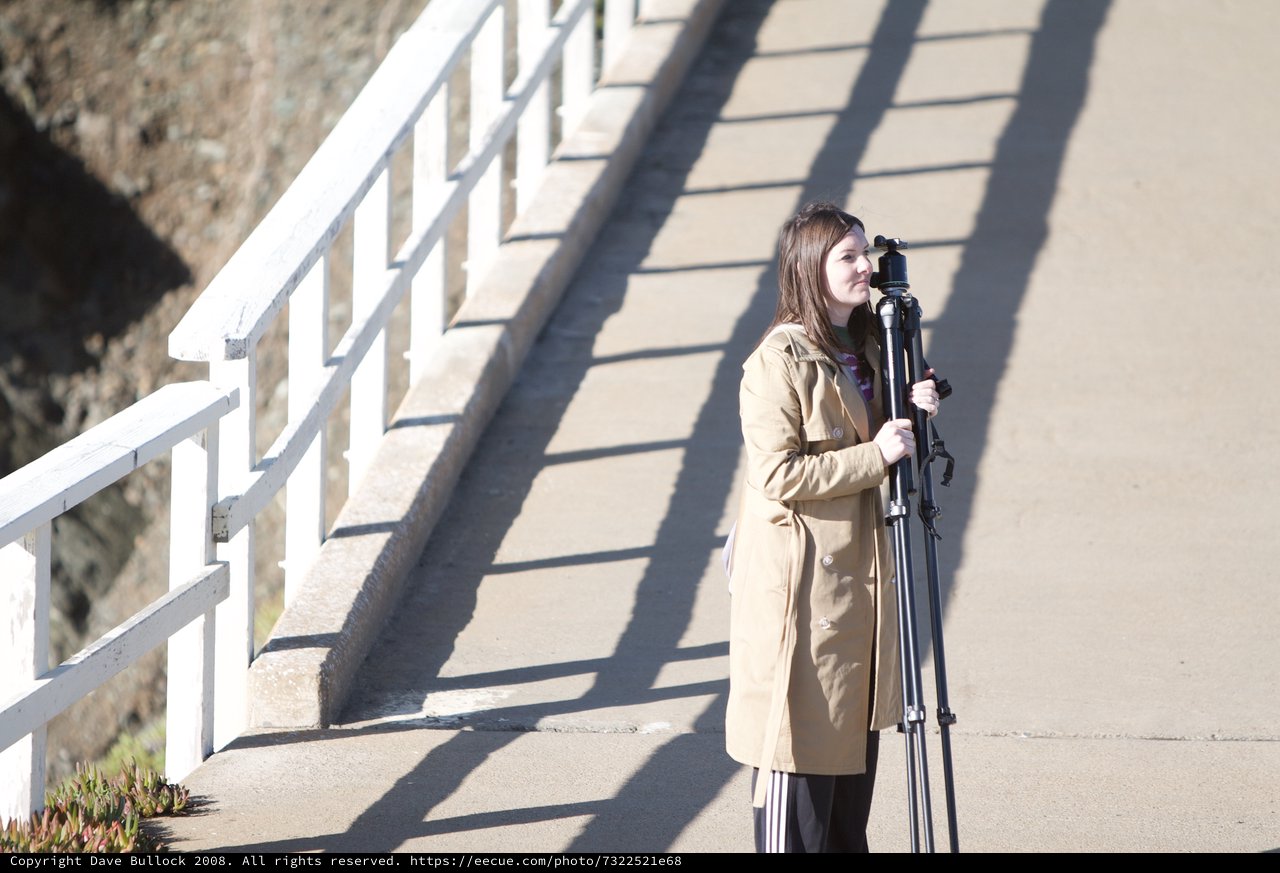 Photographer with Tripod on Sunlit Bridge Walkway