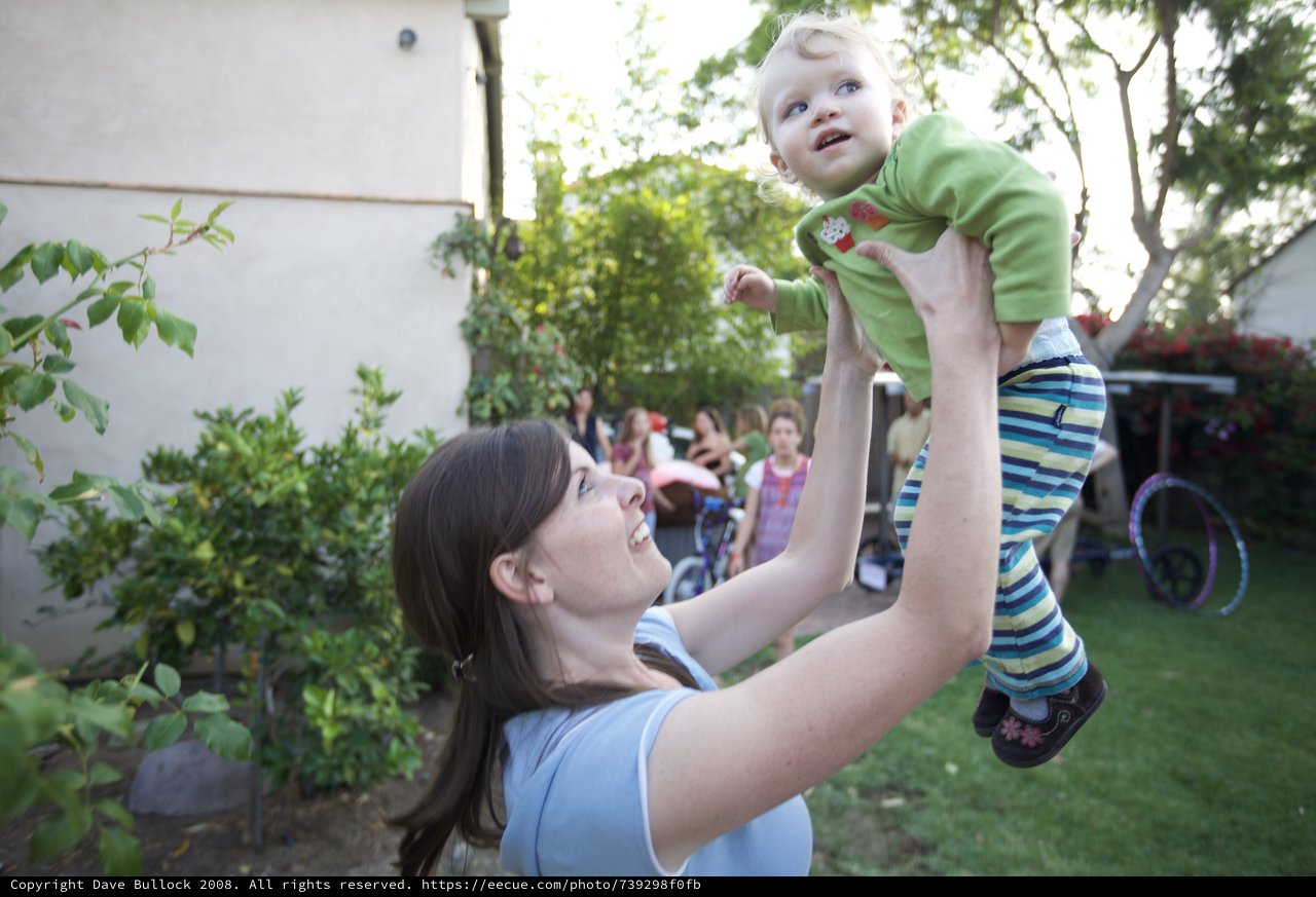 Joyful Mother Lifts Baby High in Backyard