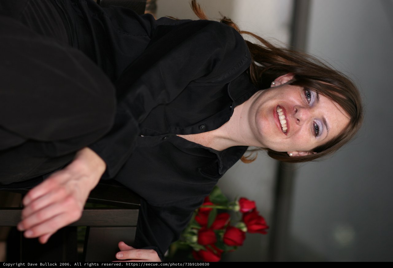 Smiling Woman in Black Seated with Red Roses