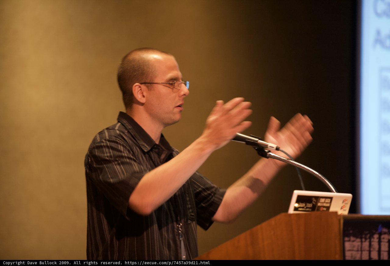 Conference speaker presenting with microphone and laptop