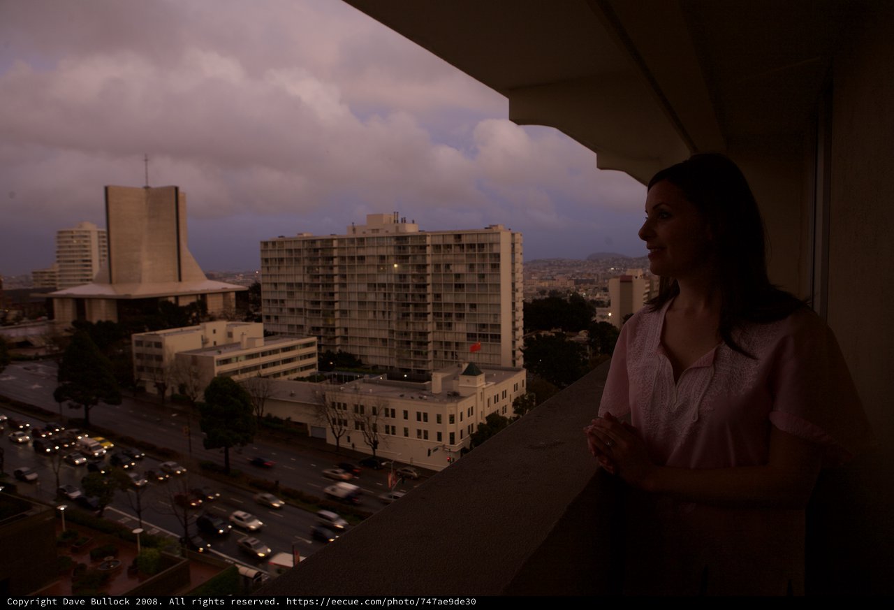 Woman Gazes Over City at Twilight from Balcony