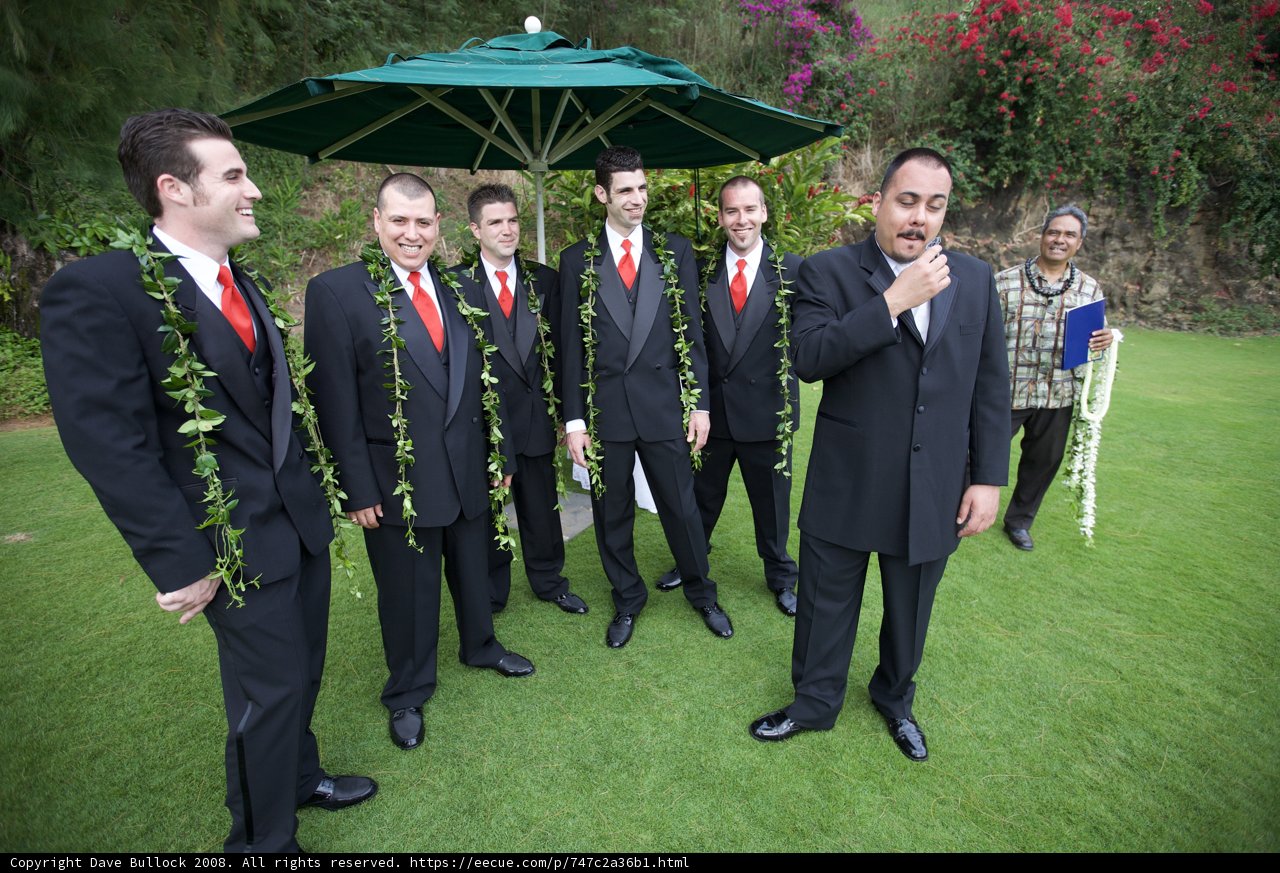 Group of men in suits under an umbrella