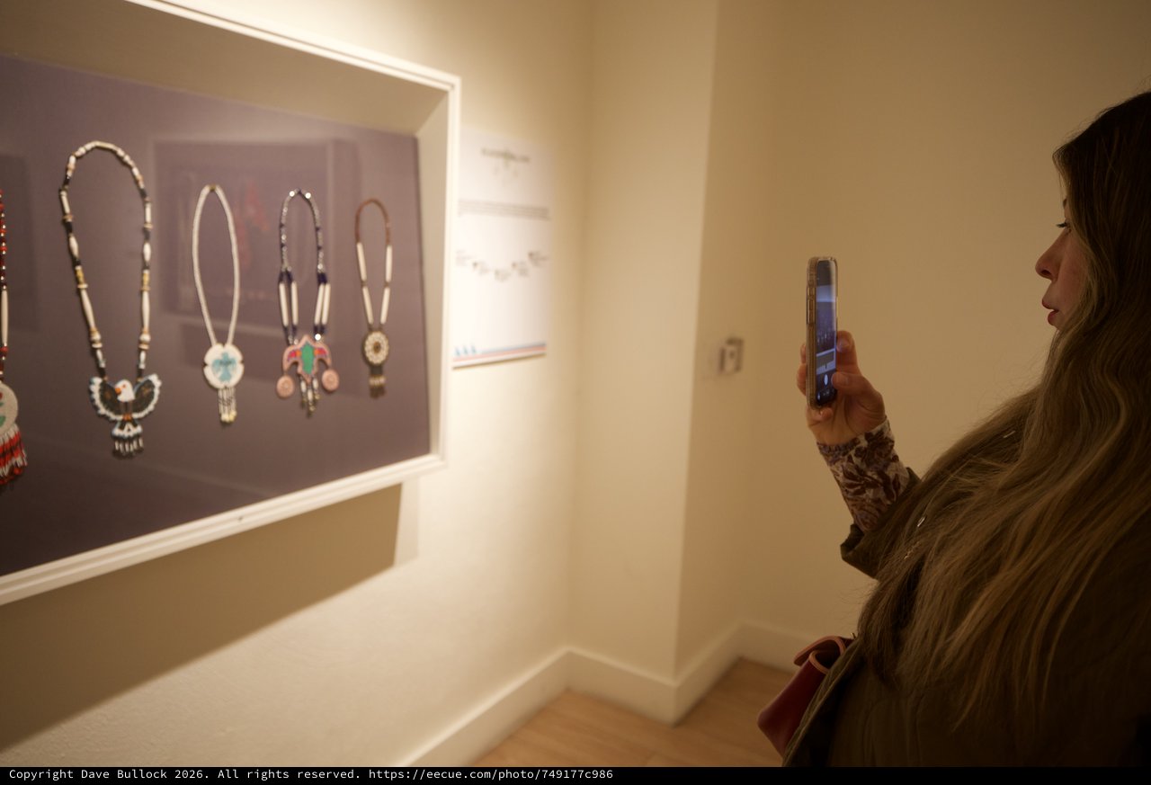 Visitor Photographing Native American Jewelry Display in Museum