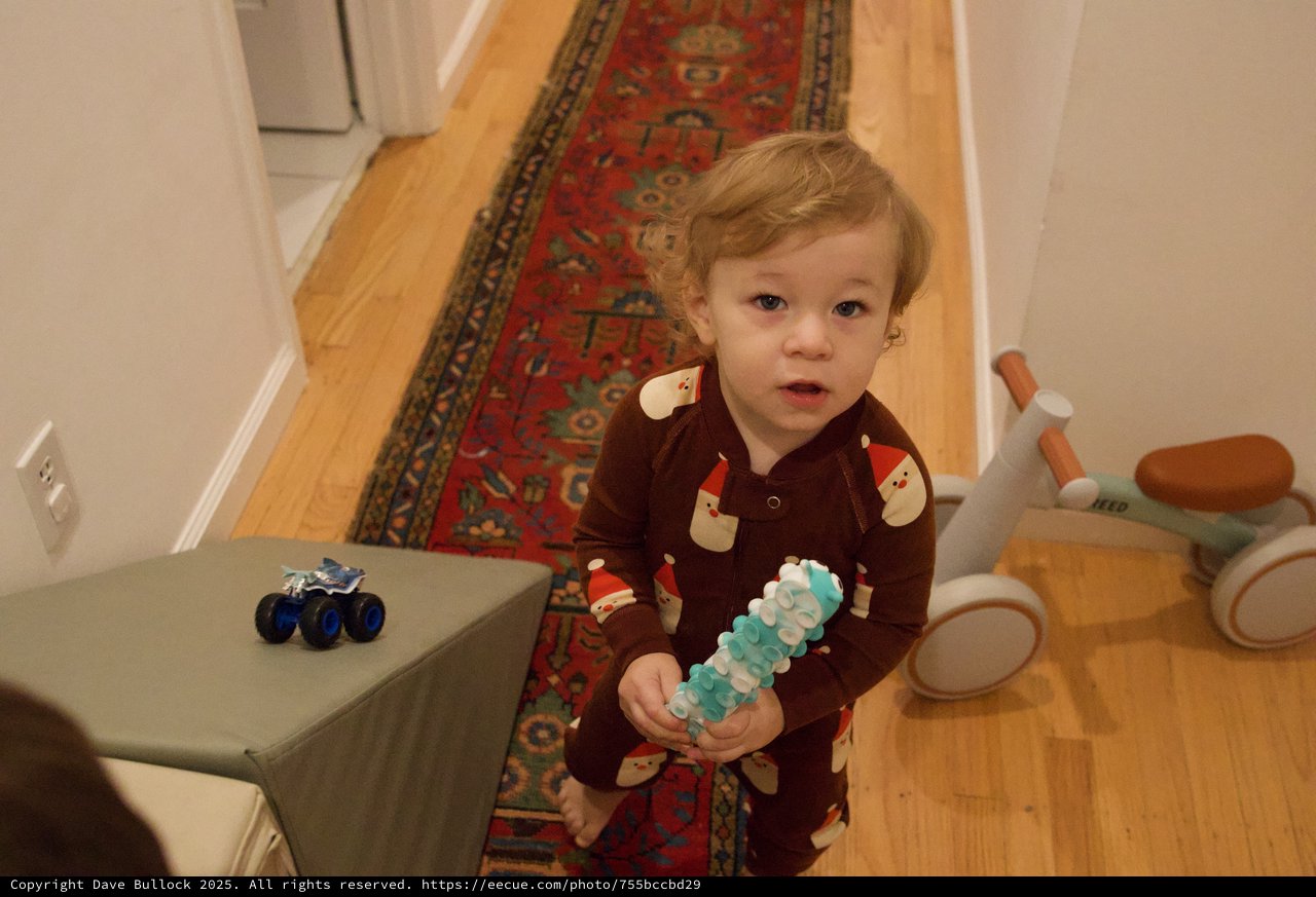 Toddler in Santa Pajamas Holding Christmas Toy