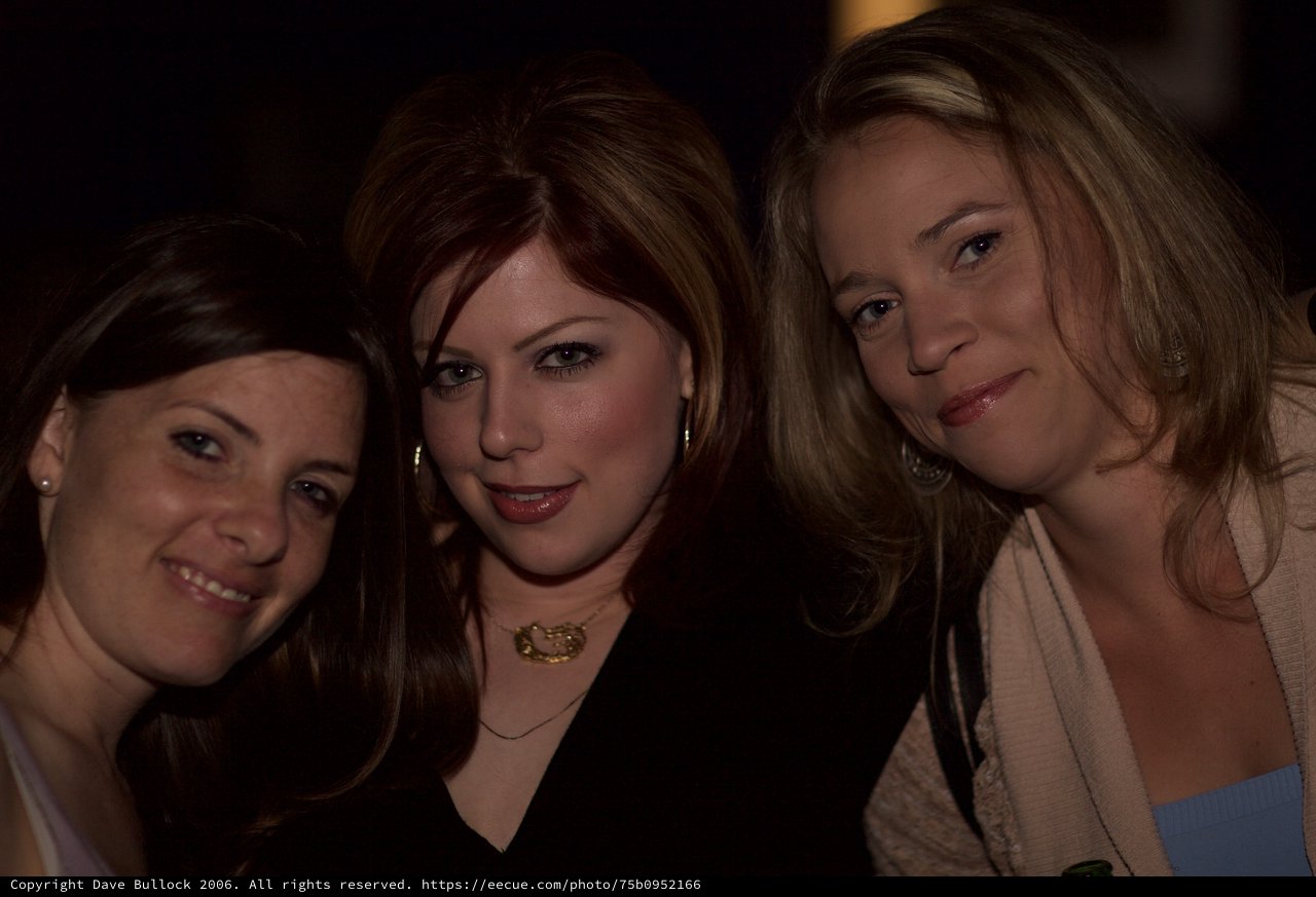 Three Women Smiling Together at a Nighttime Venue