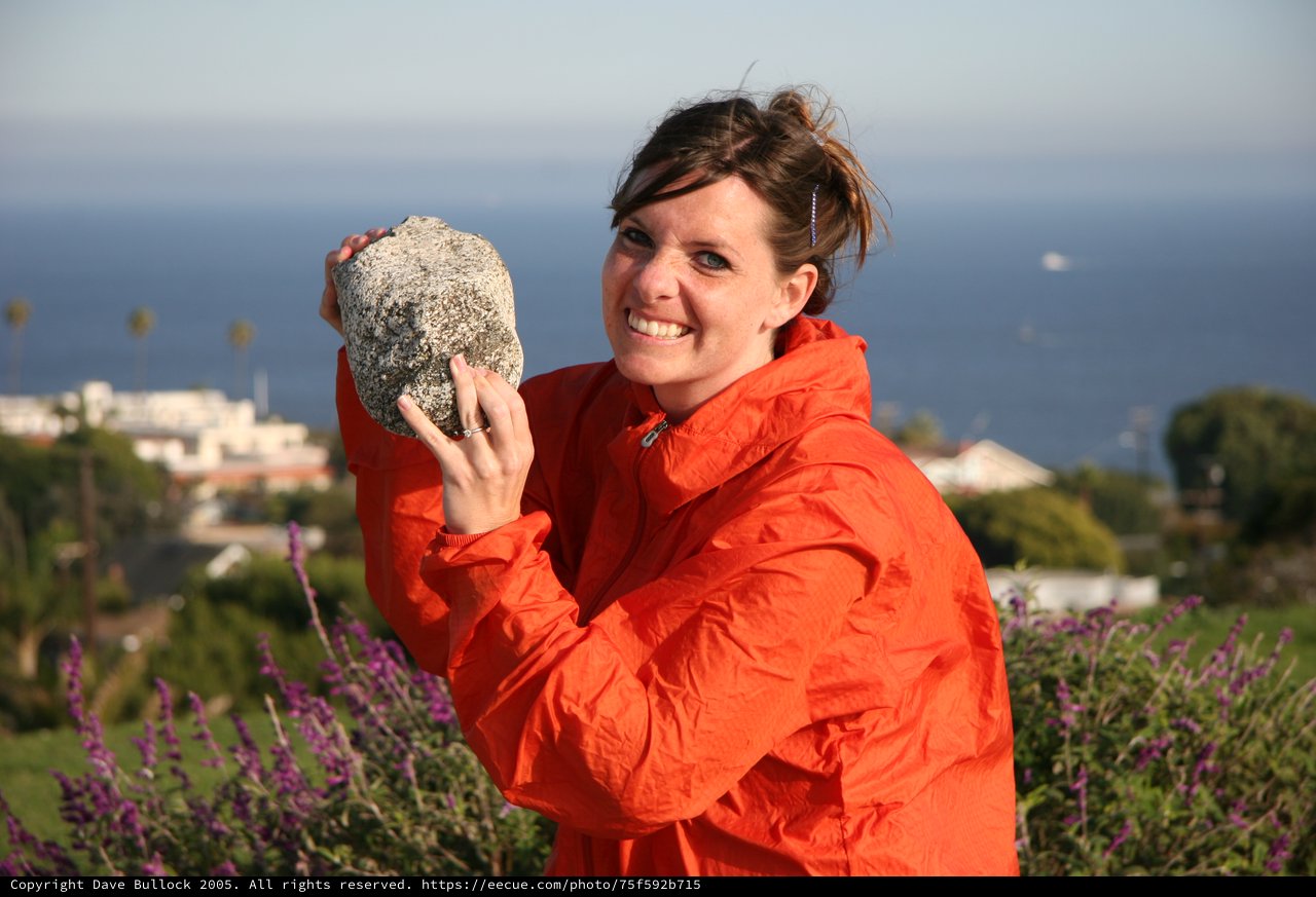 Woman Proudly Displays Large Rock by the Sea