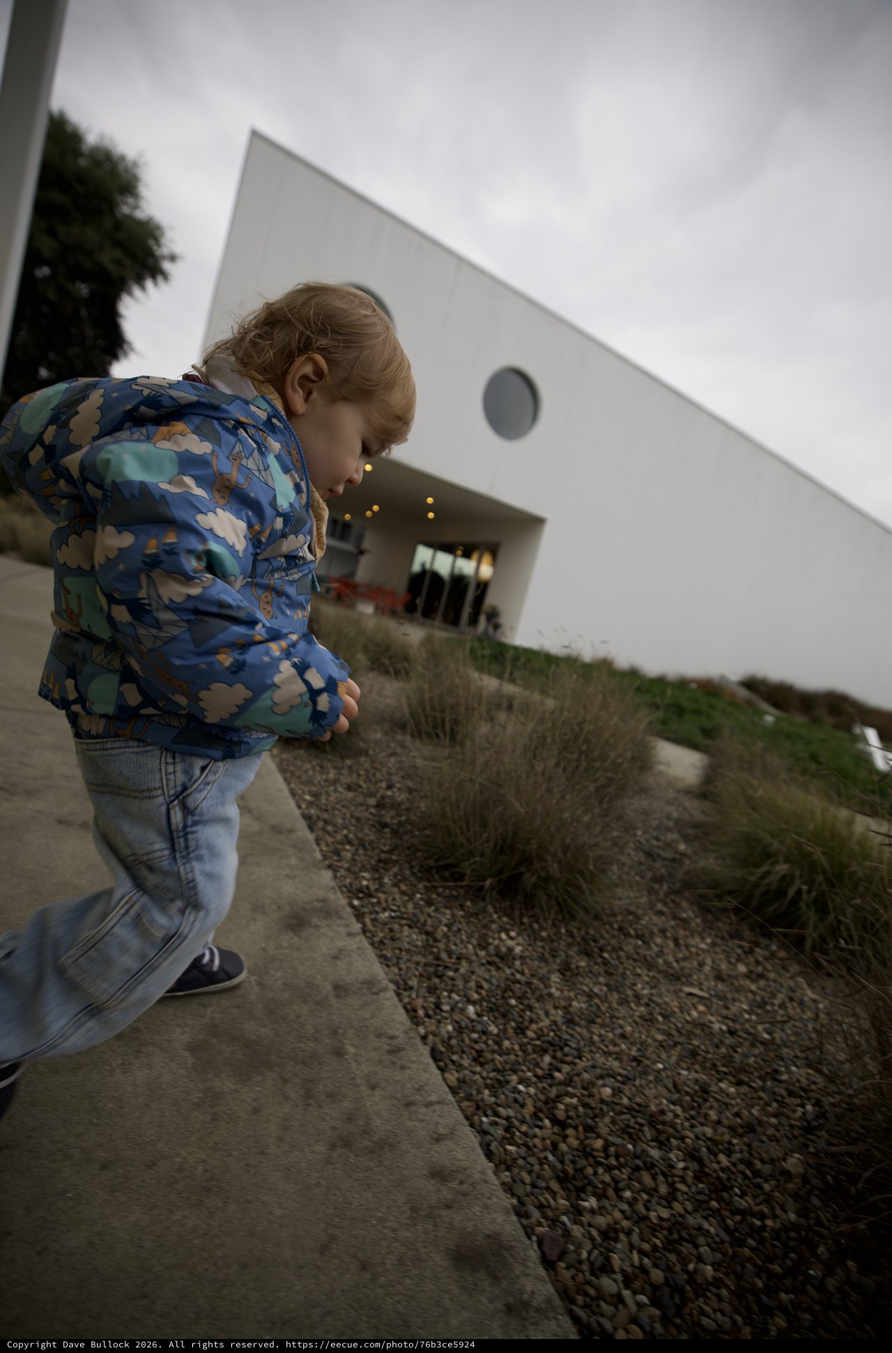 Child Exploring Modern Architecture in Overcast Weather