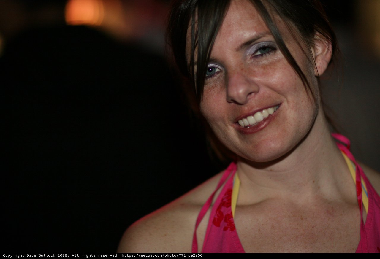 Smiling Woman in Pink at a Nighttime Event