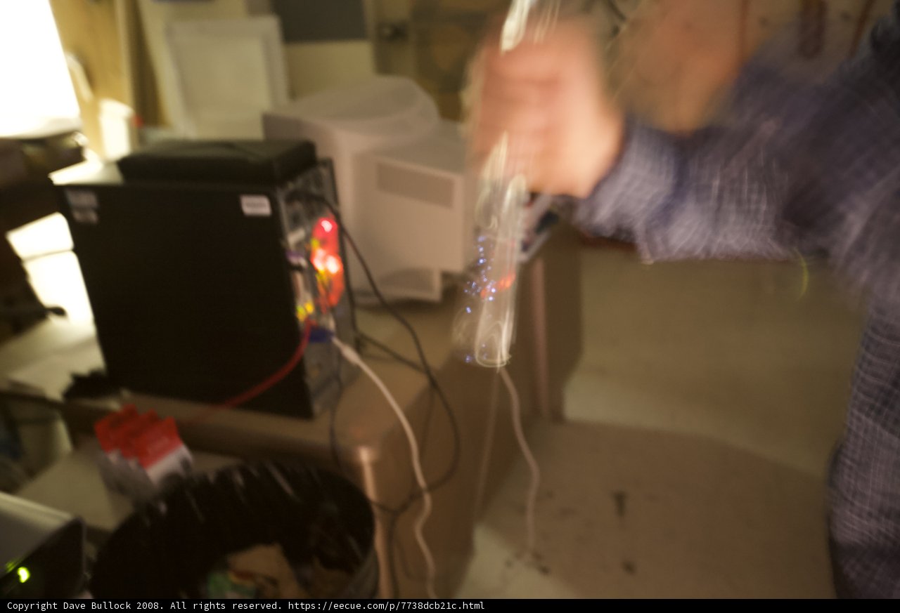 Blurred Hand Holding Glass on Tech-Filled Desk