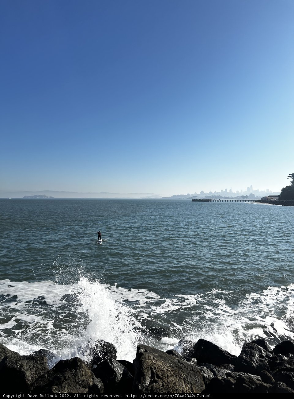 Surfer Riding the Waves by the Rocks