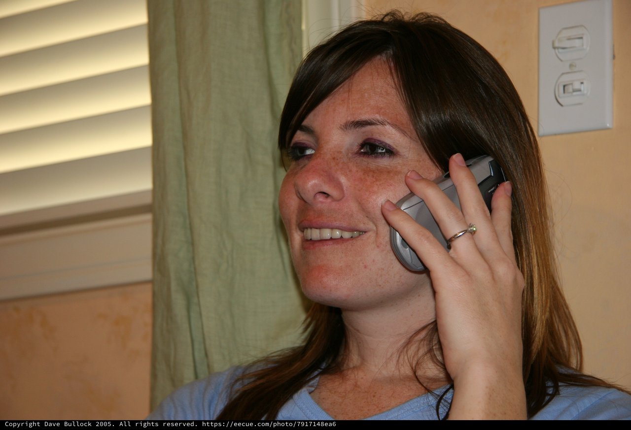 Young Woman Smiling While Talking on Flip Phone