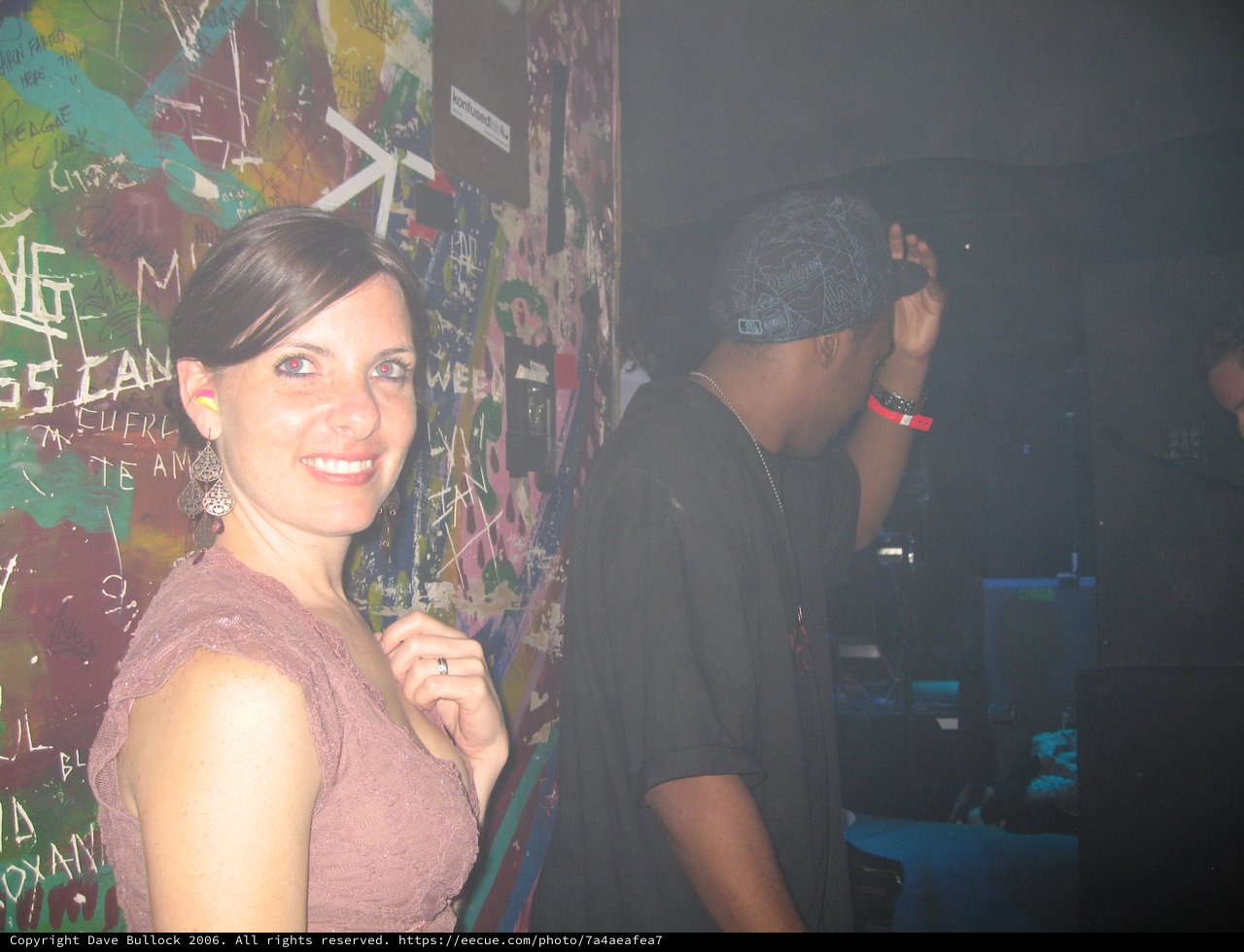 Smiling Woman at Graffiti-Covered Nightclub Wall