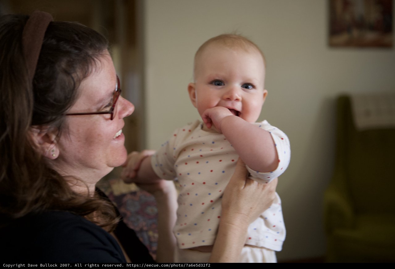 Joyful Mother Holds Laughing Baby in Warm Home