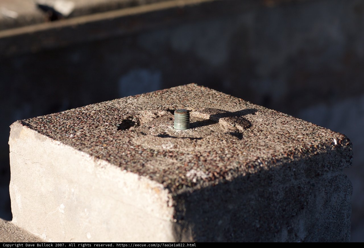 Industrial Heritage: A Rusty Screw on Cement Block