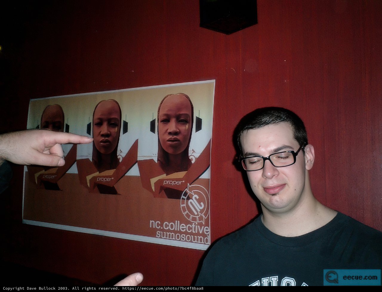 Dave B pointing at a three-person poster