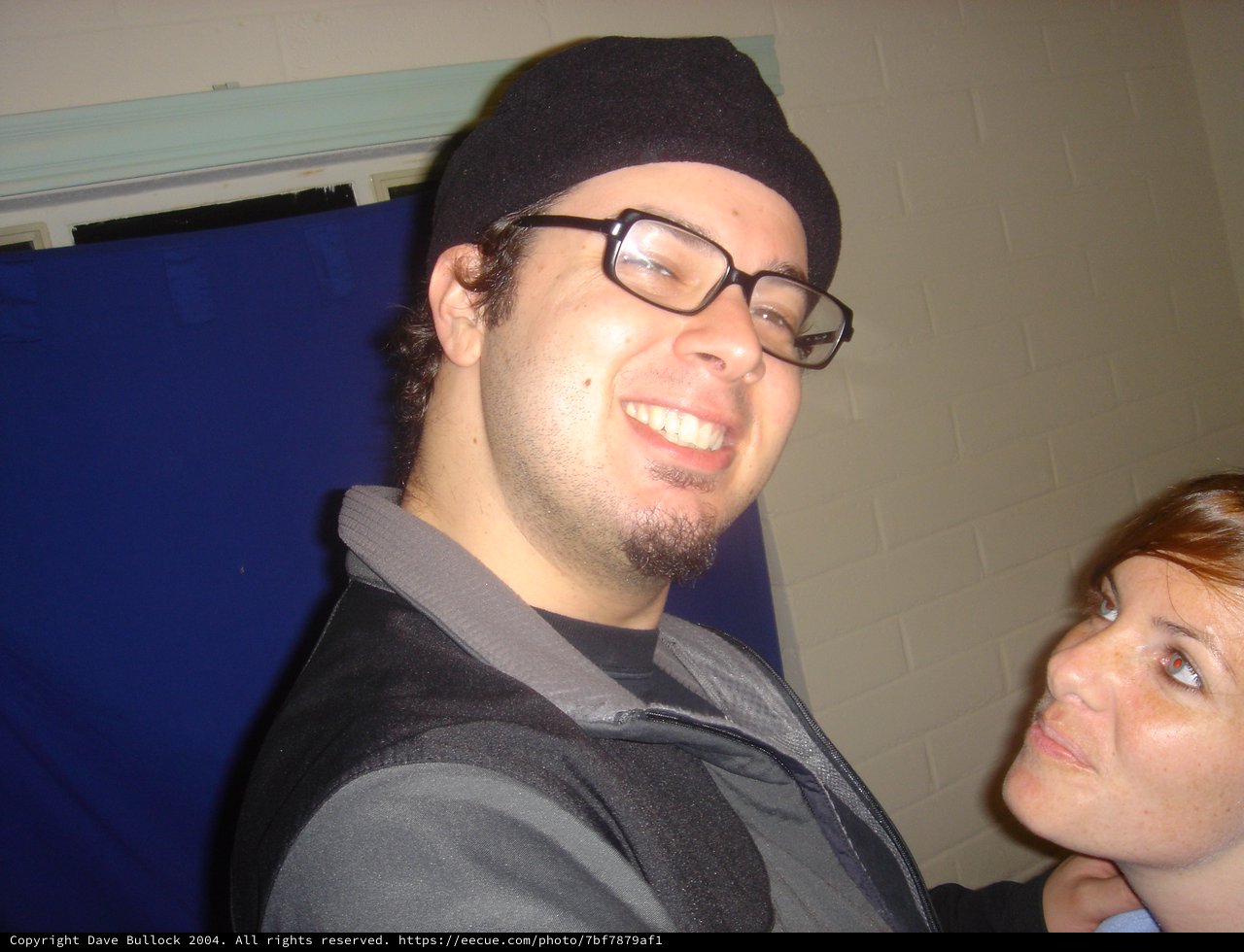 Smiling Man in Black Beanie at Indoor Gathering
