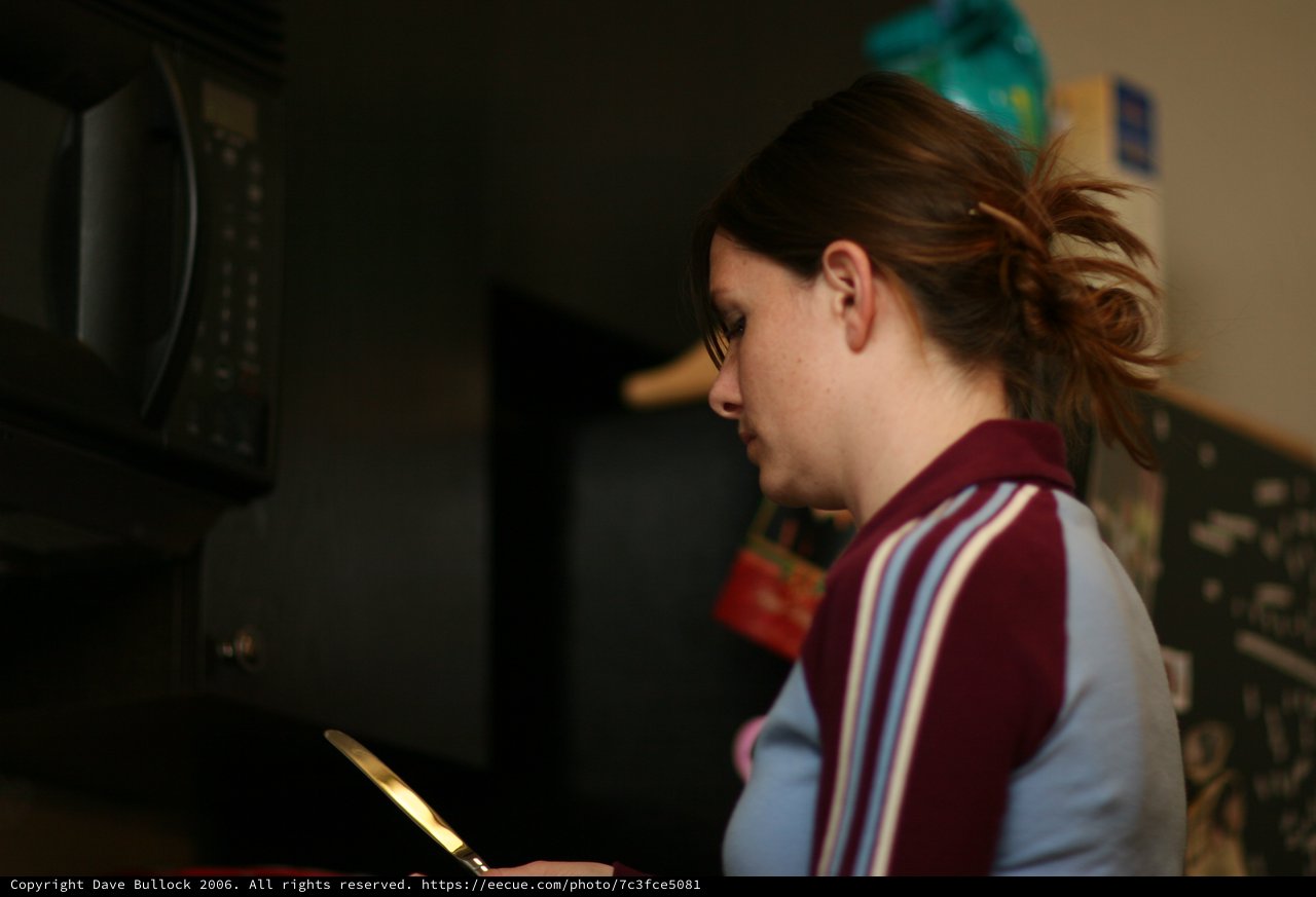 Young Woman Focused in Dimly Lit Kitchen