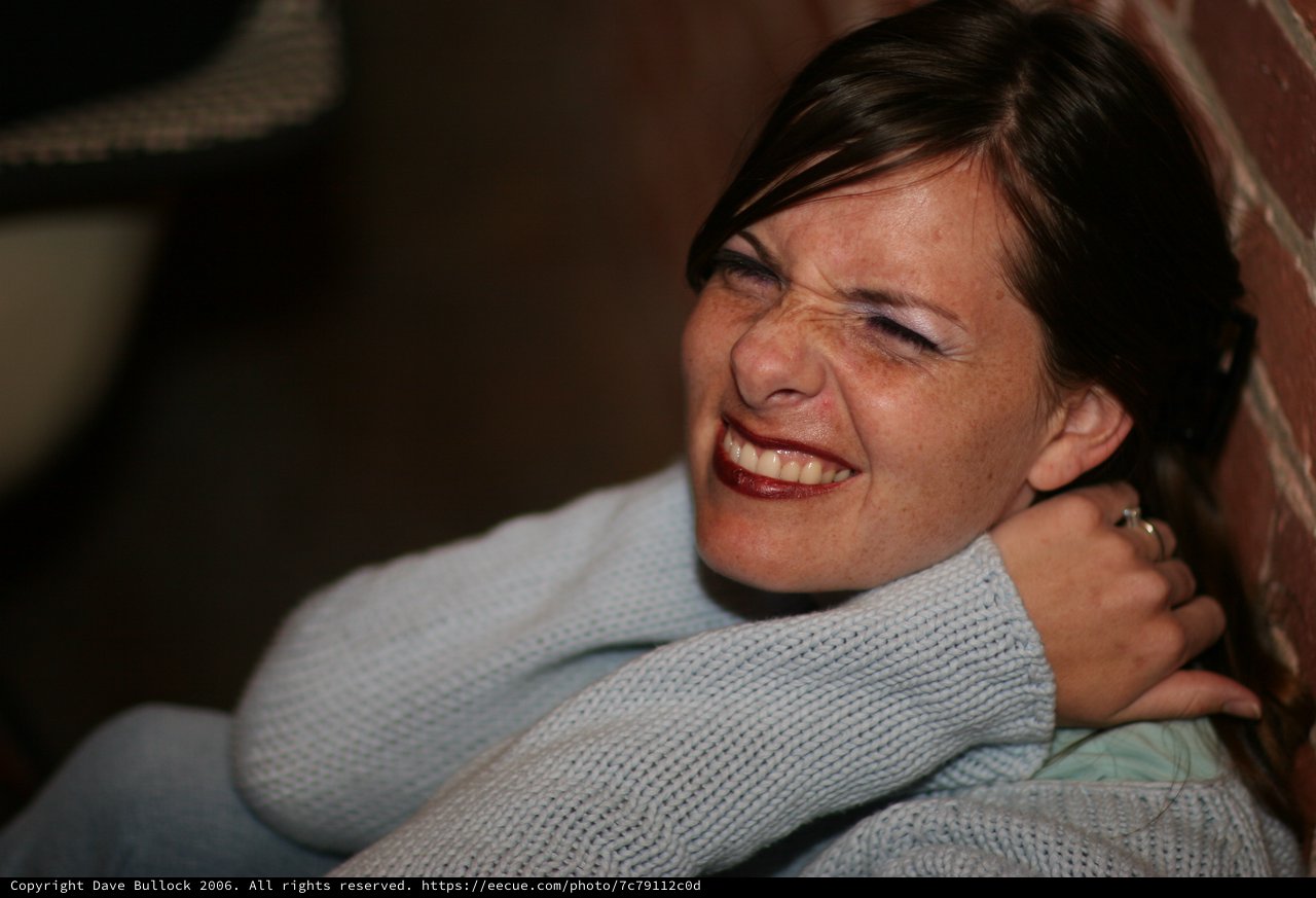 Joyful Woman Laughing Against Brick Wall