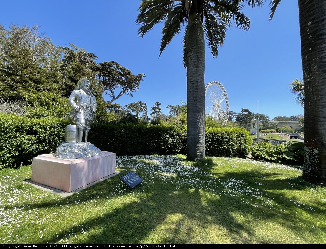 Statue in a Park with Palm Trees and Ferris Wheel