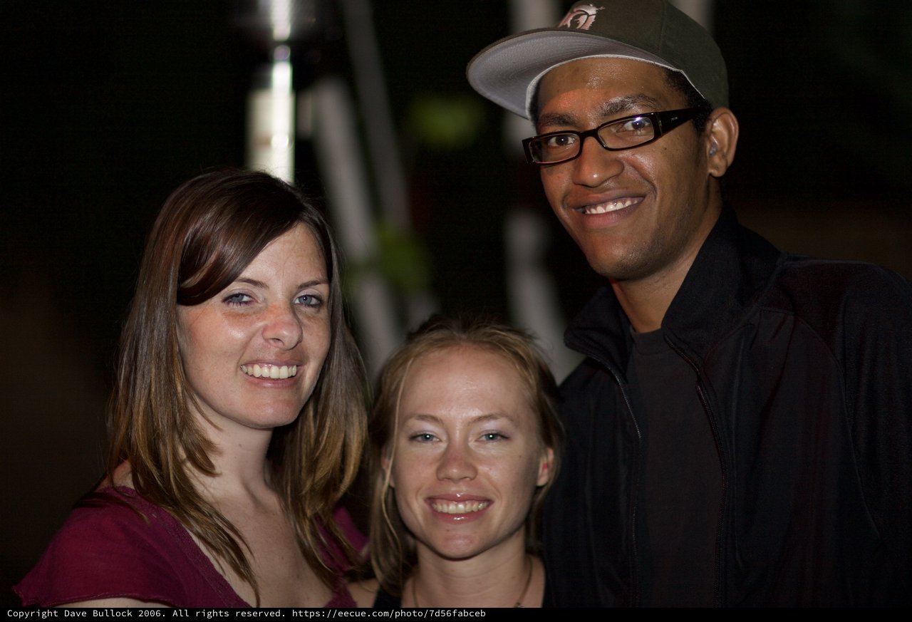 Three Friends Smiling Together at Night Event