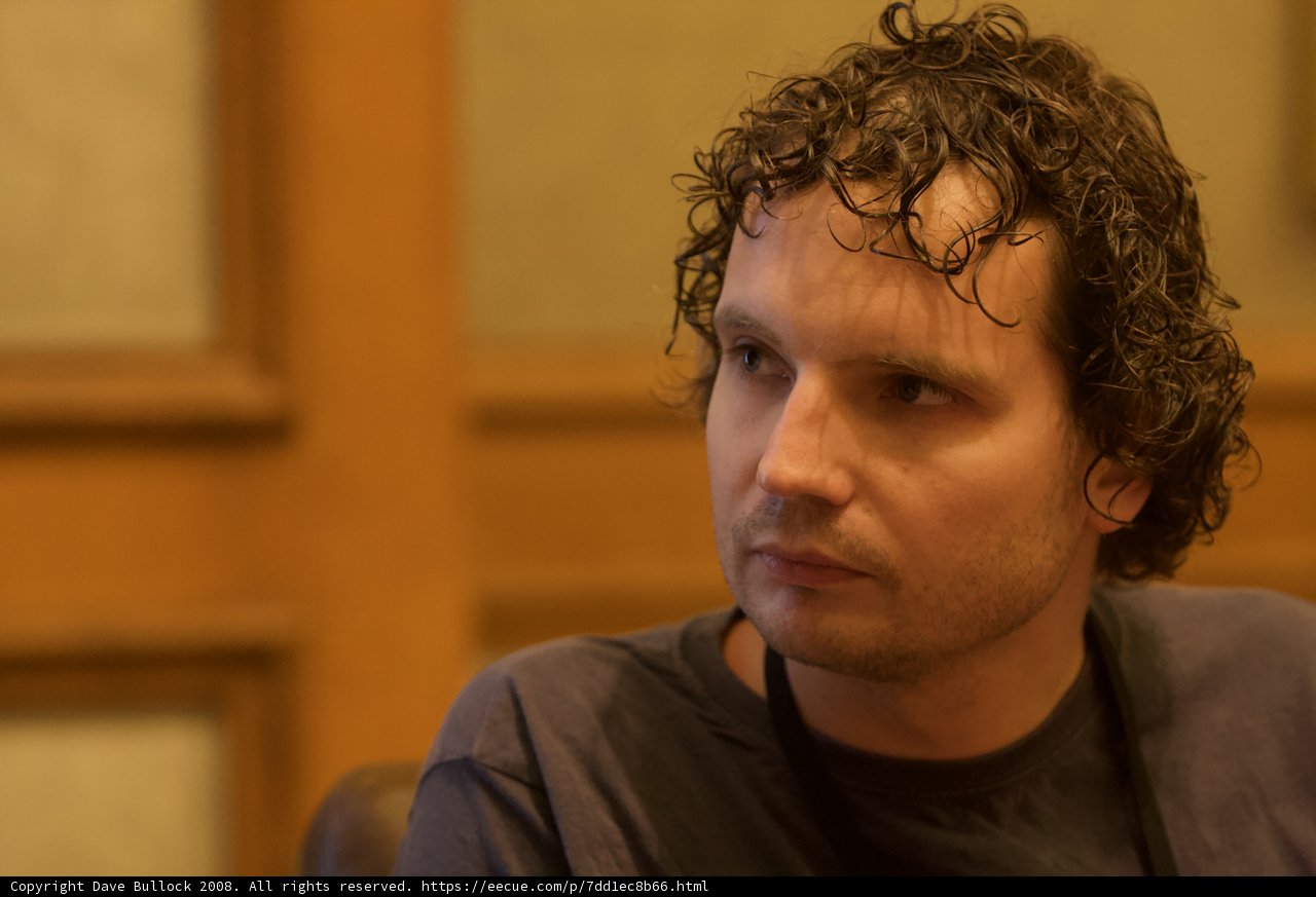 Curly Haired Man in Wooden Chair