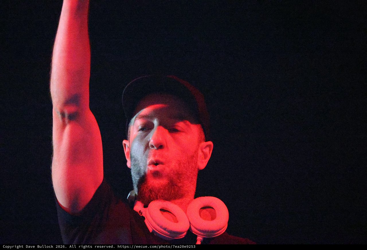 DJ Raises Hand Under Red Stage Lights at Wobbleland
