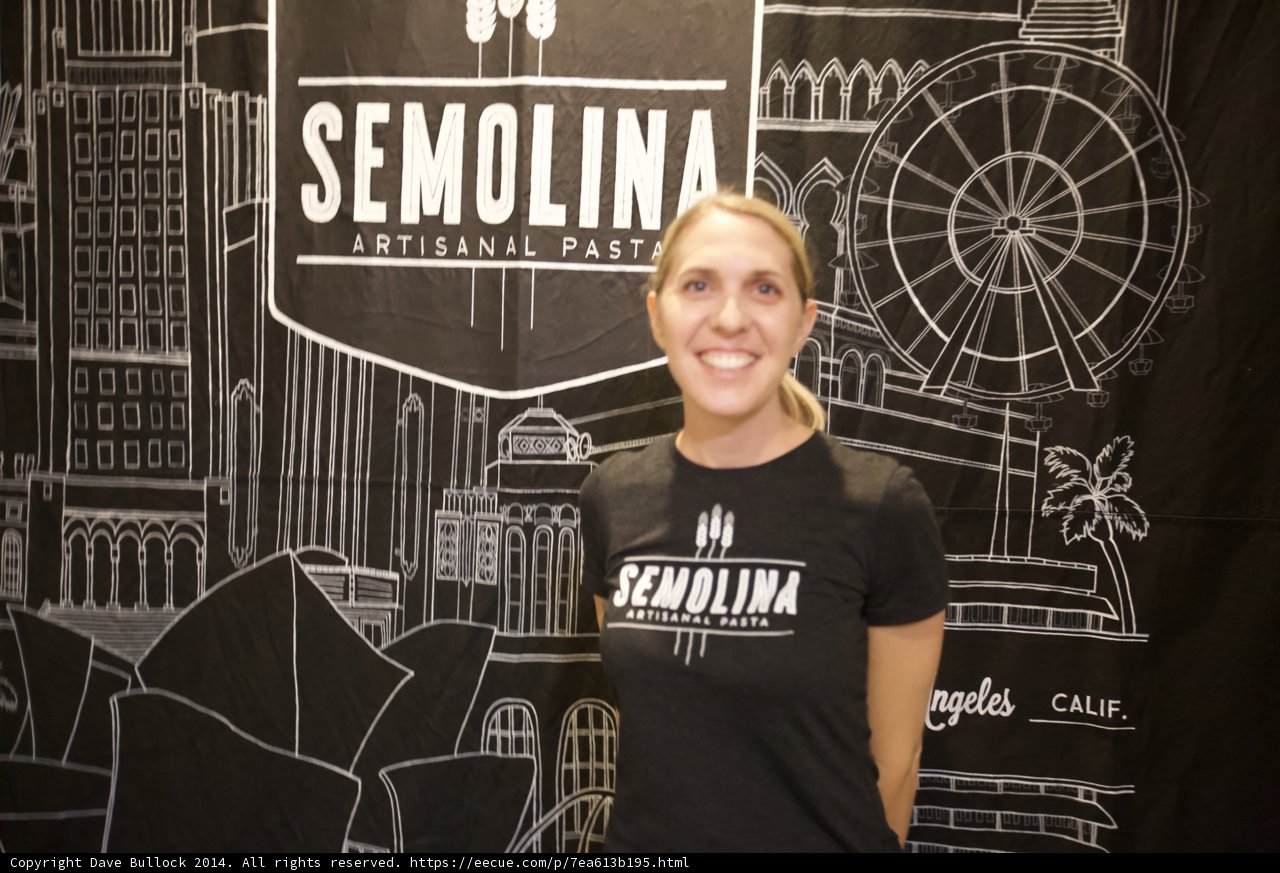 Smiling Woman Poses in Front of Semolina Sign