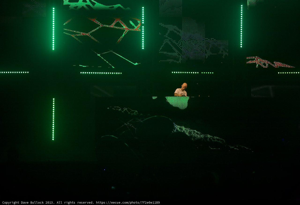 Moby performs on stage with green screen and lighting at Coachella