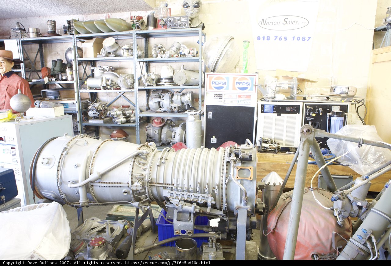 Man Standing in Front of Massive Engine at Factory