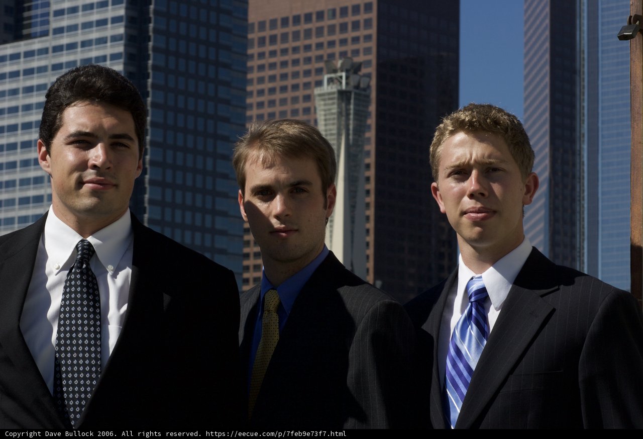 Three Men Pose in Front of a City Building