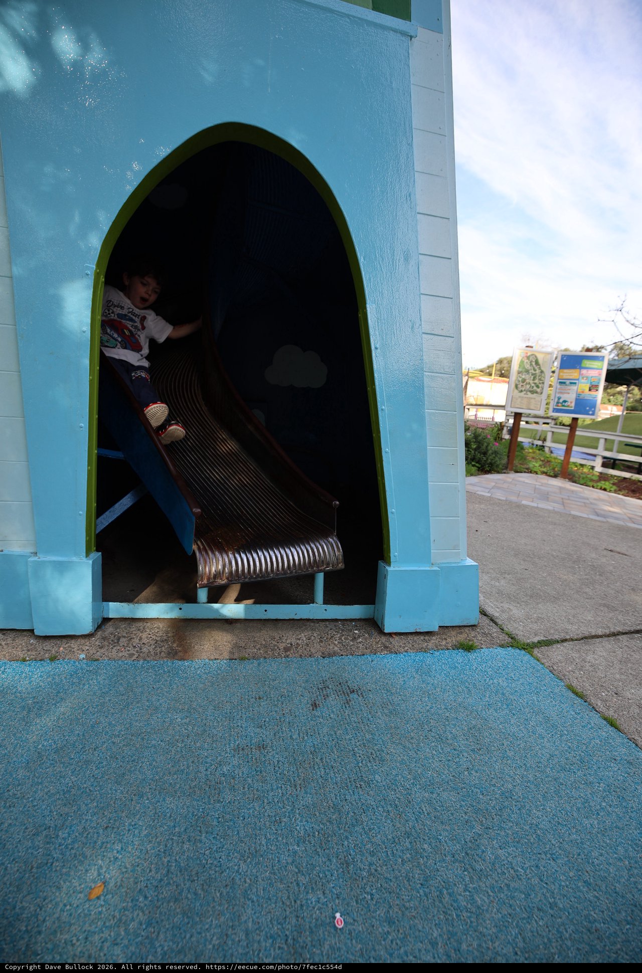 Child Playing in Blue Tunnel Slide at Playground