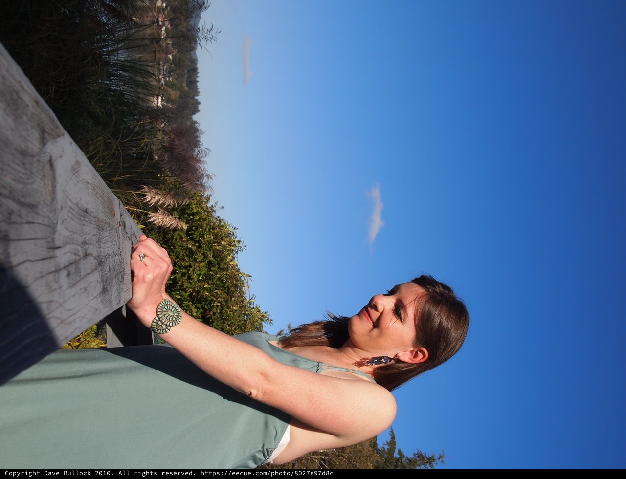 Woman in Teal Dress Gazes Skyward at Outdoor Venue