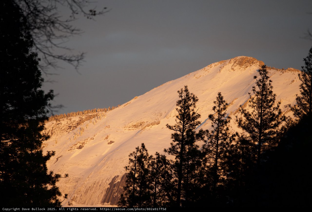 Golden Alpenglow on Snow-Covered Mountain Peak at Dusk