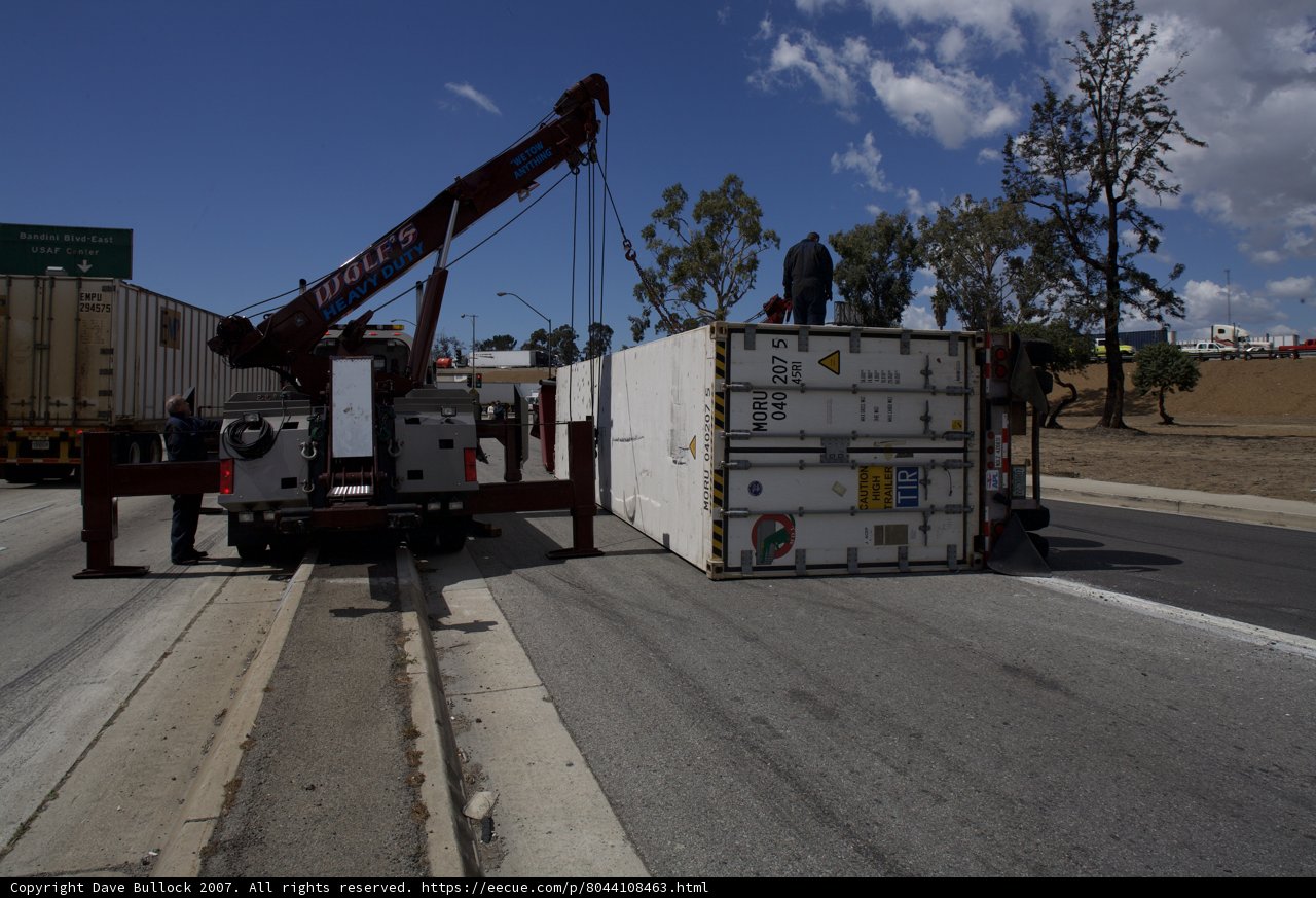 Container lifted onto truck by crane.