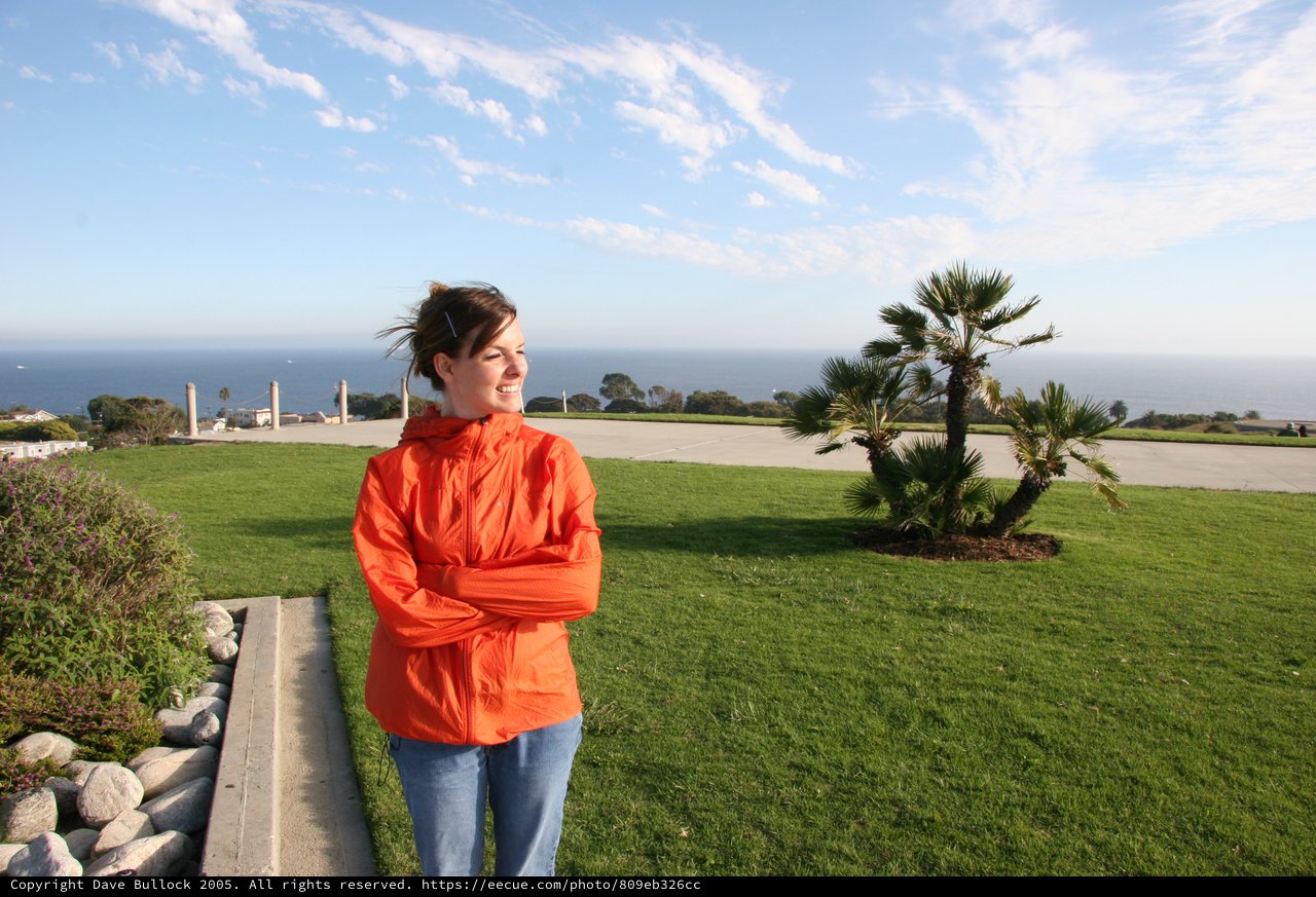 Smiling Woman at Coastal Overlook on Windy Day