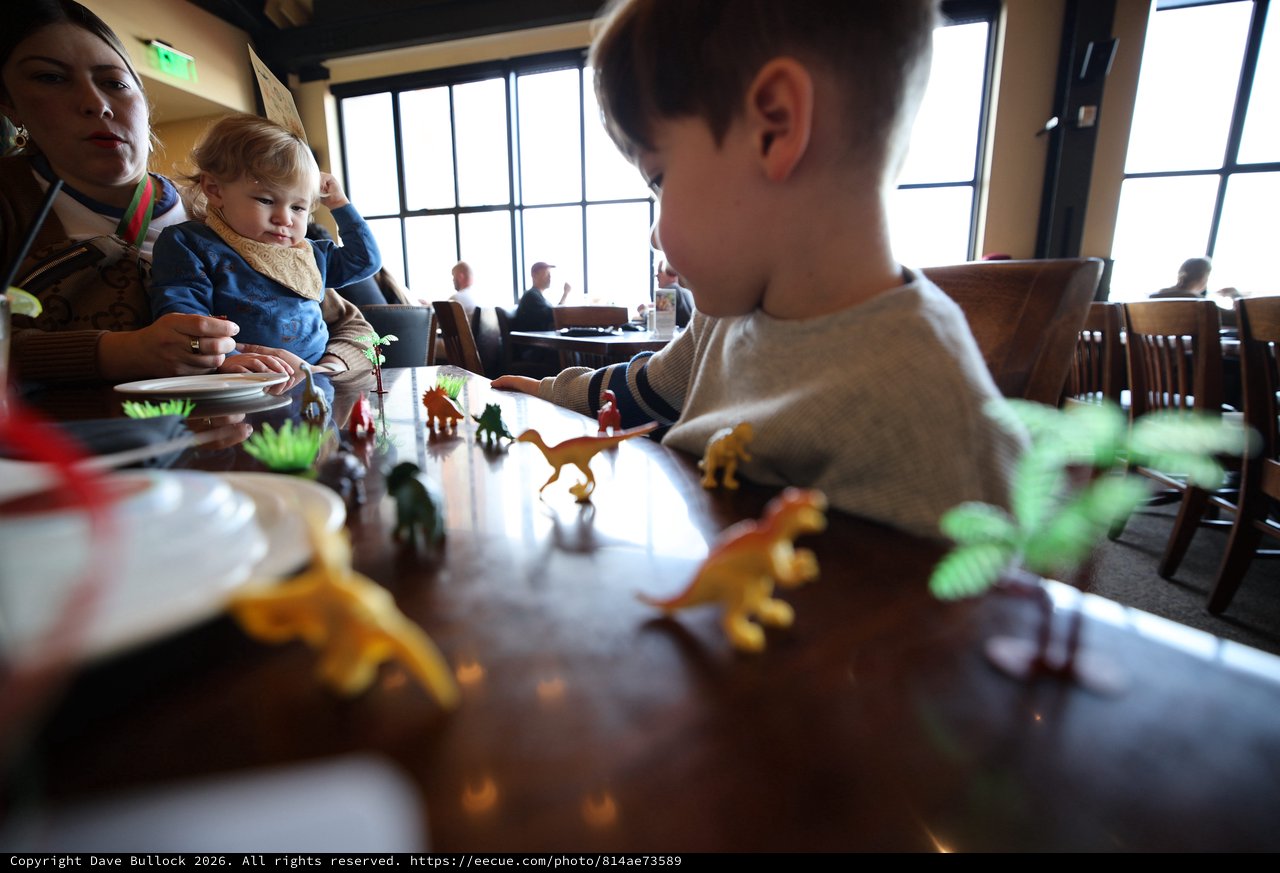 Children Playing with Dinosaur Toys at Restaurant Table