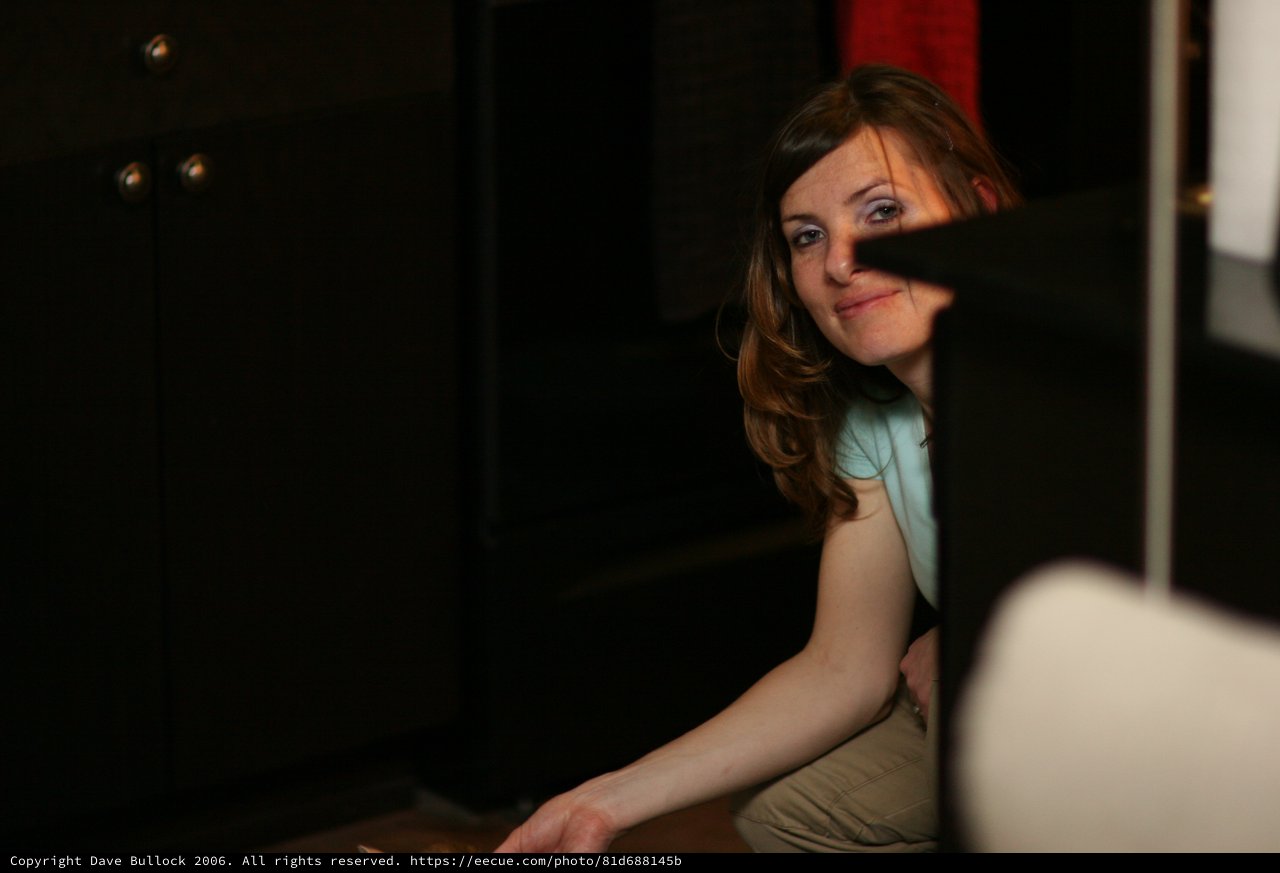 Curious Woman Peering Around Dark Furniture