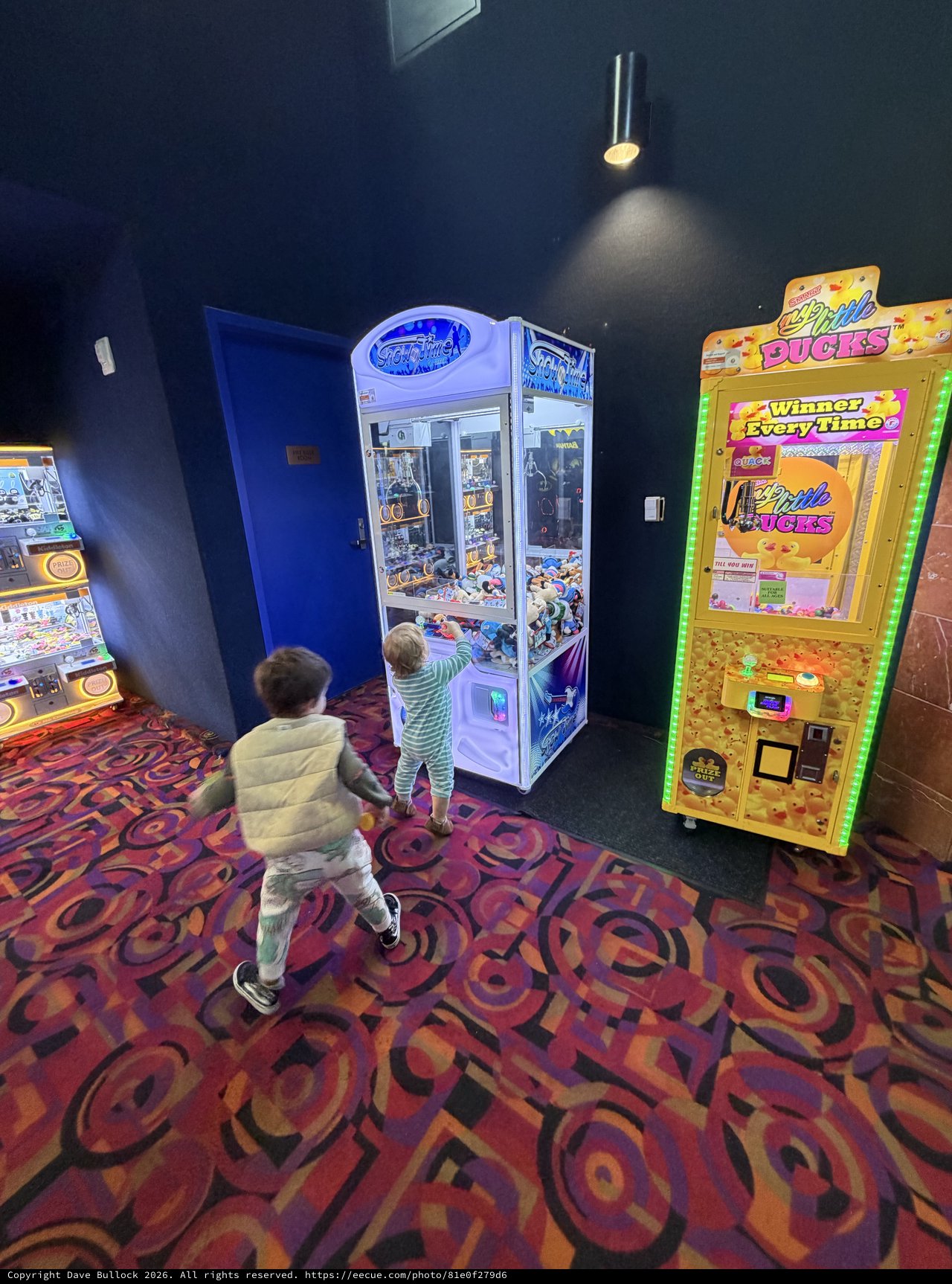 Children Playing Arcade Claw Machines in Game Room