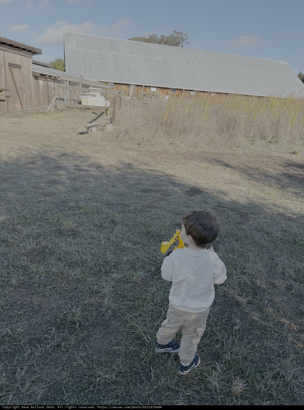 Child Playing with Yellow Toy in Rural Farm Setting