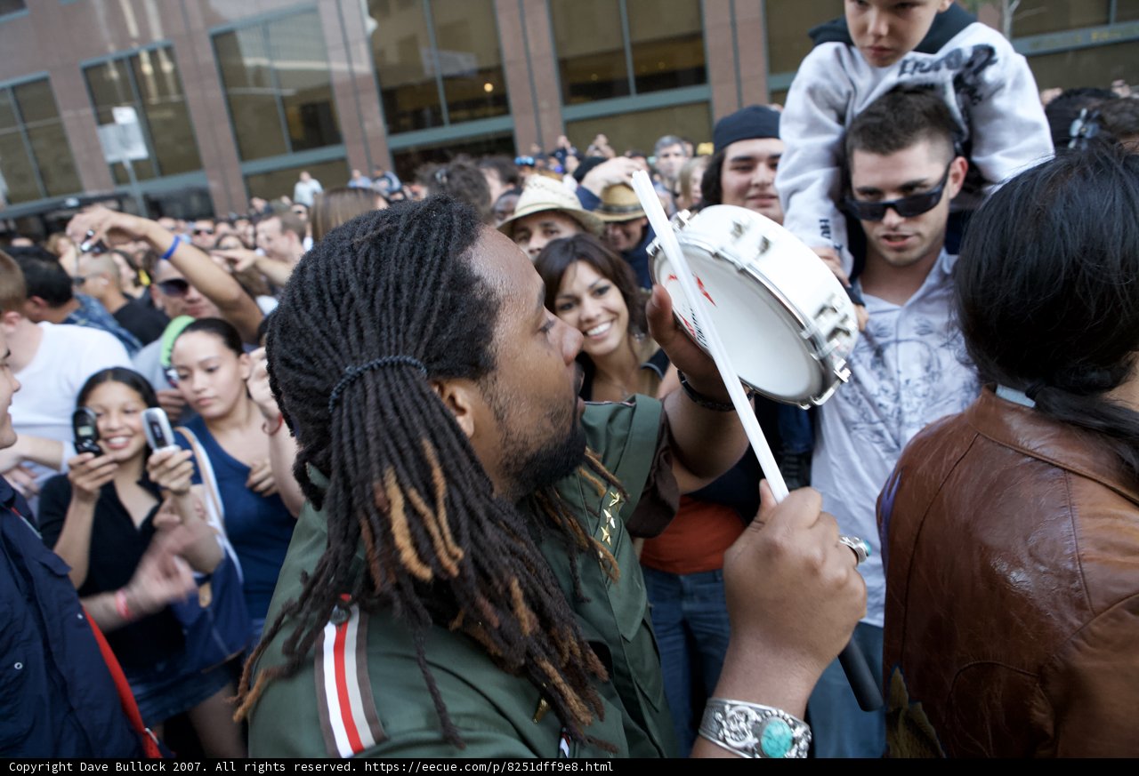 Dreadlocked man playing the tambourine at Ozomatli concert