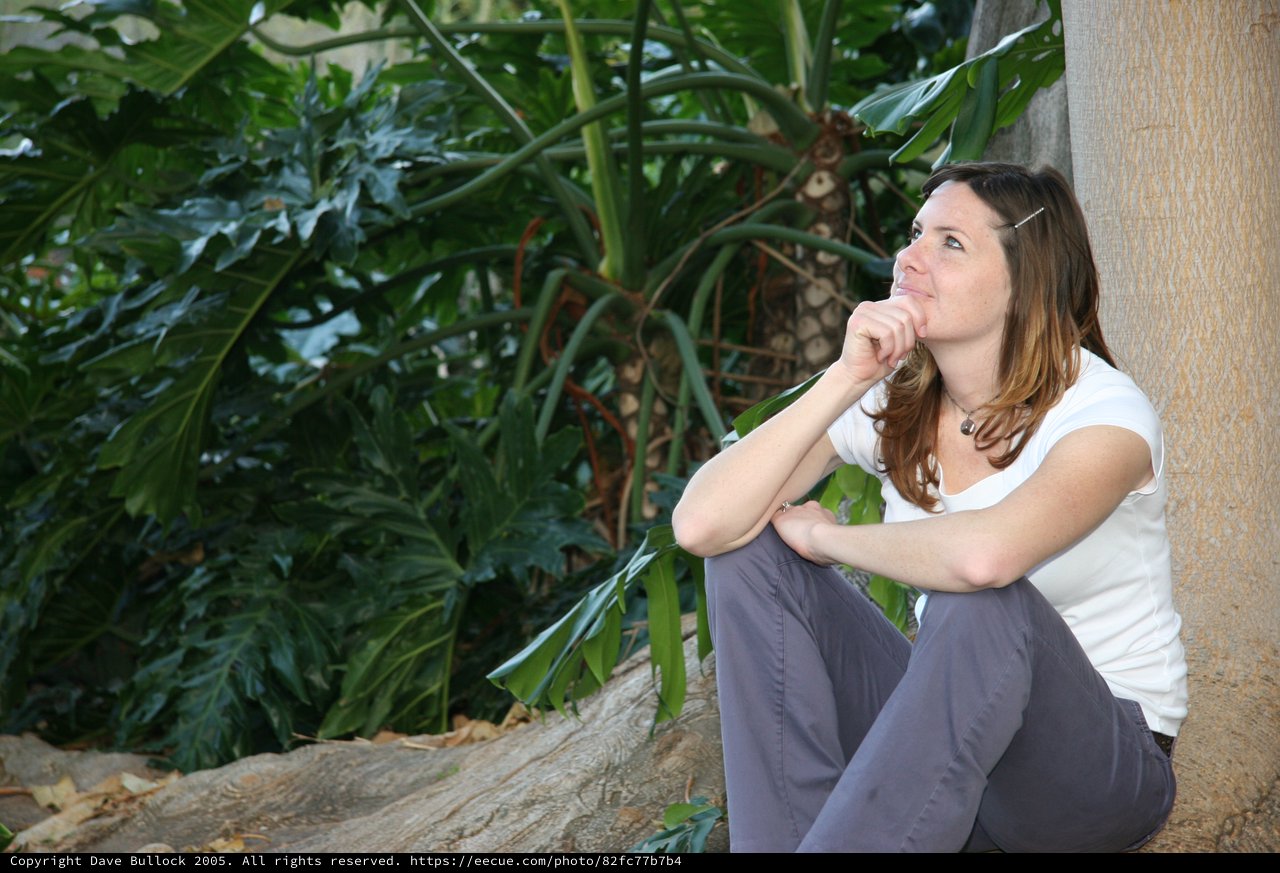 Contemplative Woman Resting Against Wall in Tropical Garden