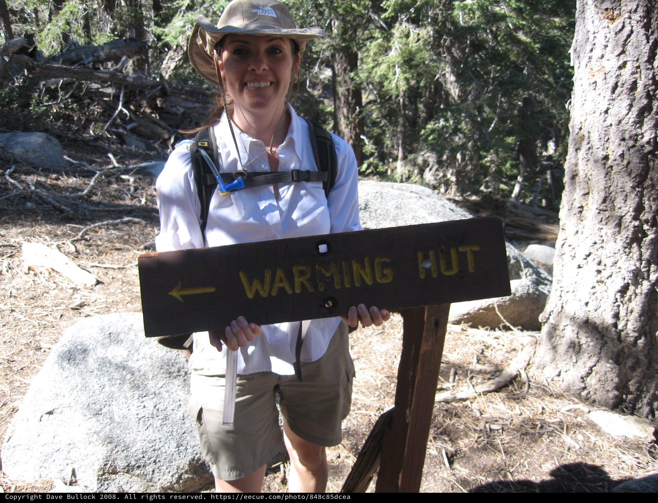 Hiker Poses at Warming Hut Trail Sign